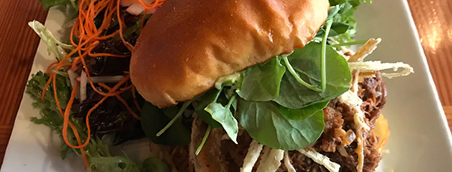 Lum Farms Goat Sandwich & a side of mixed greens at the Cask & Schooner